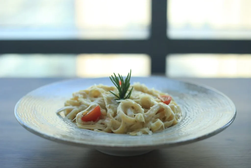 Close-up shot of cheesy fettuccine pasta with herbs.
