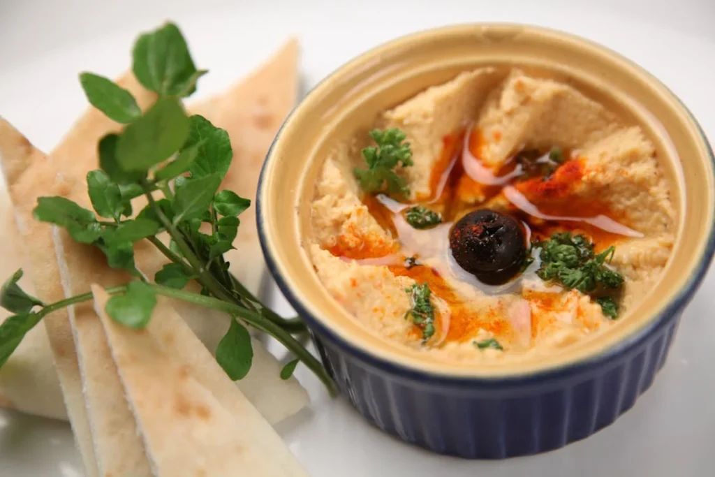 Creamy hummus with olive oil drizzle served alongside warm pita slices at Manny & Olga’s in DC.