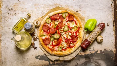 Shot of a delicious topping-rich pizza with salami, peppers, and mushrooms.